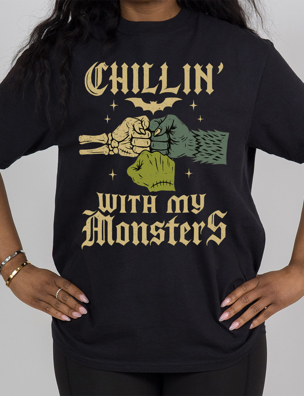black modern tee with the words "chillin' with my monsters" around the graphic of a skeleton's hand, a werewolf's hand, and a zombie's hand, doing a fist pump, with a bat above, and few stars around