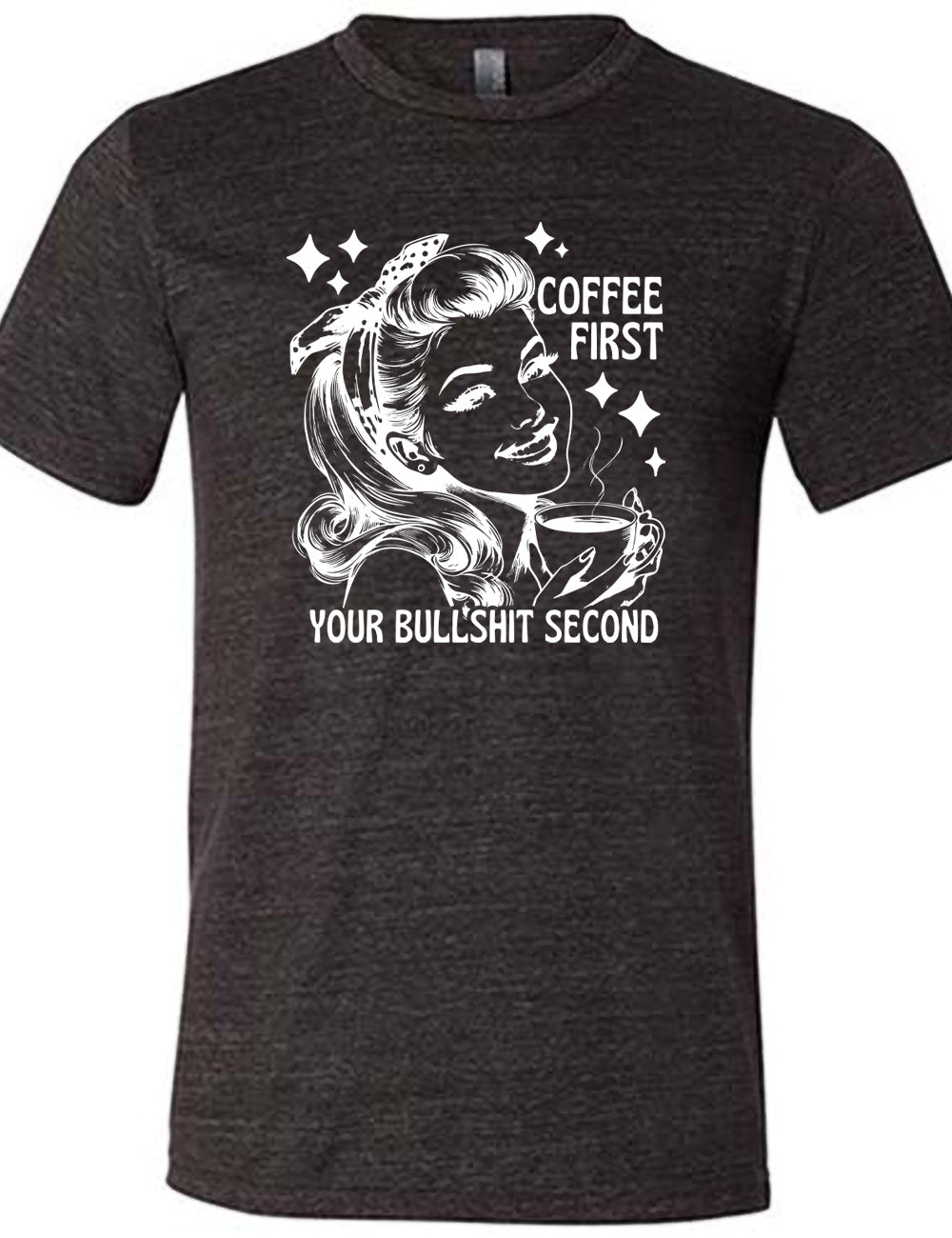 black unisex tee with the graphic of a woman happily holding a mug of steaming coffee, with the words "coffee first" (next to her face) and "your bullshit second" underneath, and a few stars around her