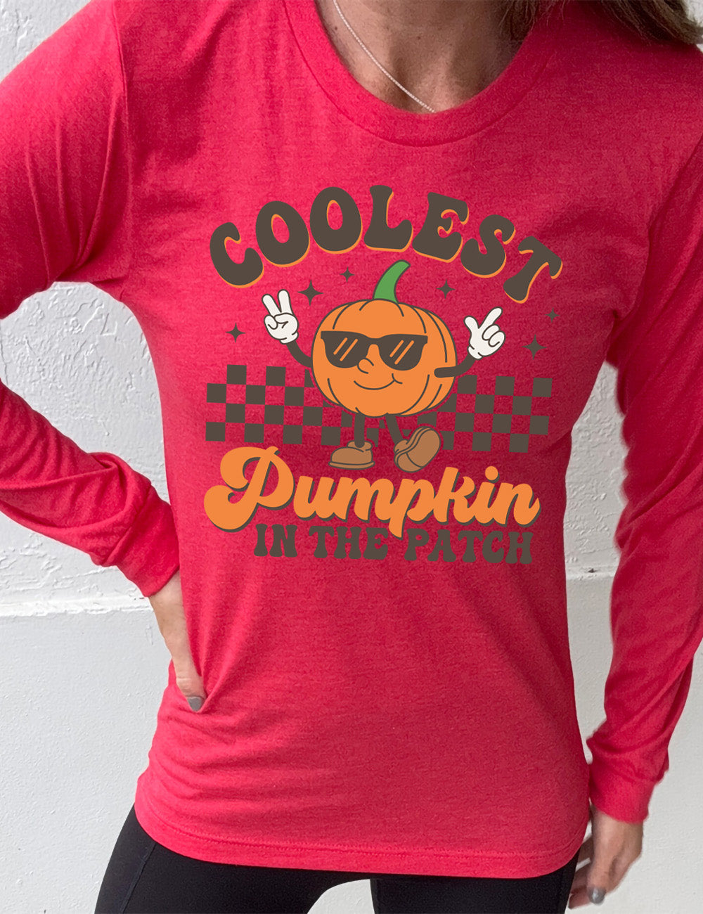 heather red long sleeve with the graphic of a pumpkin, wearing sunglasses, both arms raised, foot kicking out, in front of a checkered banner, surrounded by a few little stars, with the words around it saying "coolest pumpkin in the patch"