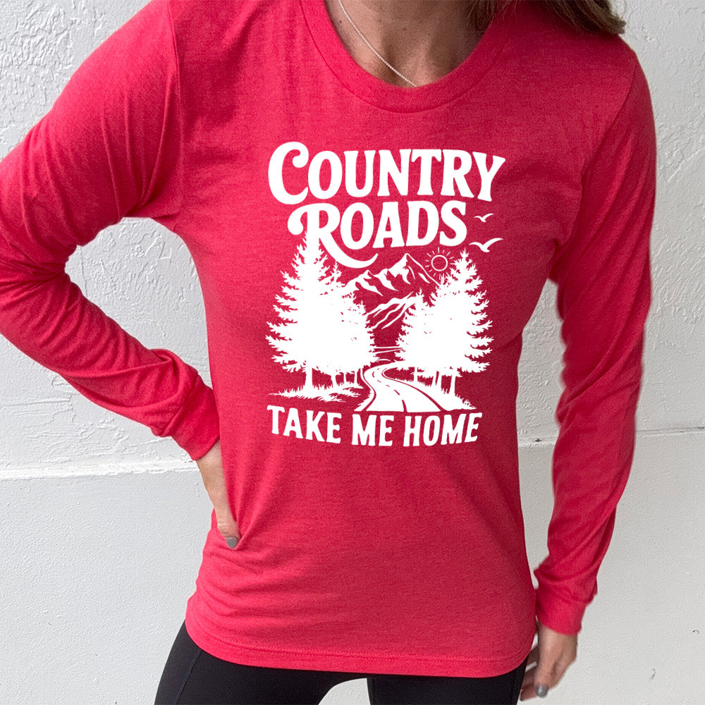 heather red long sleeve with the words "country roads take me home" on it, and the graphic of a road going through tall trees, with mountains beyond, and the sun