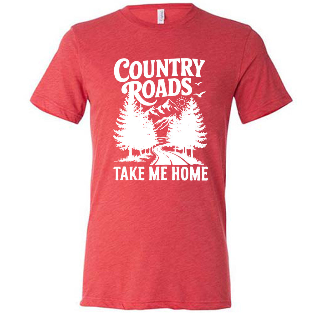 red unisex tee with the words "country roads take me home" on it, and the graphic of a road going through tall trees, with mountains beyond, and the sun