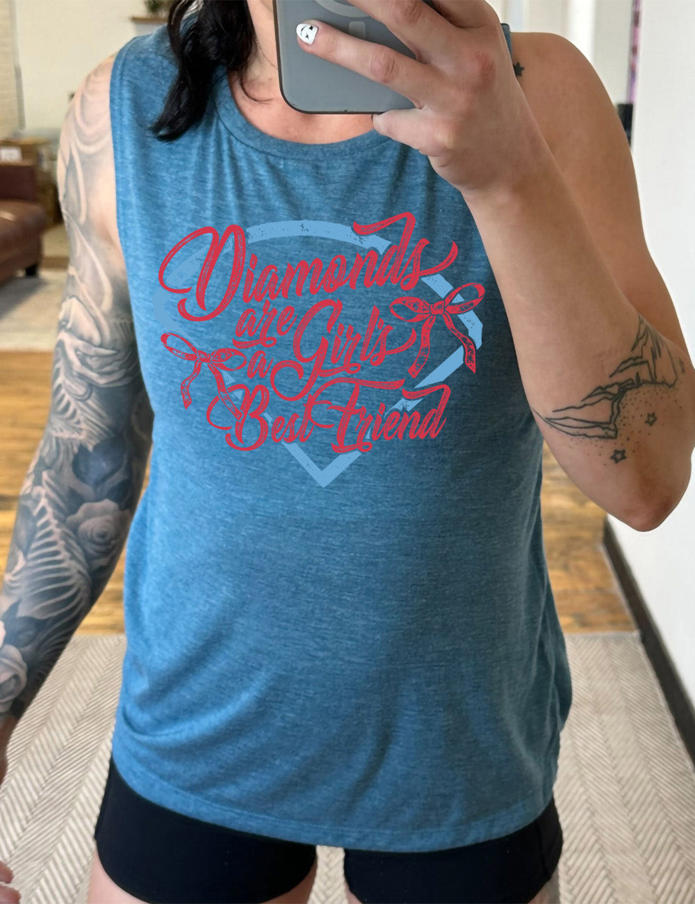 deep teal muscle tank with the words "diamonds are a girl's best friend" on it, with two bows, all in front of a baseball diamond