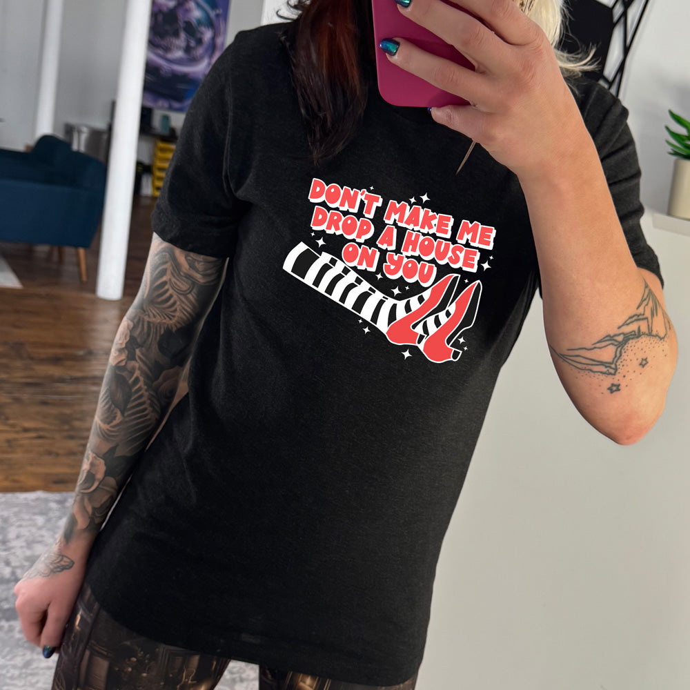 black shirt with the text "Don't Make Me Drop A House On You" on it