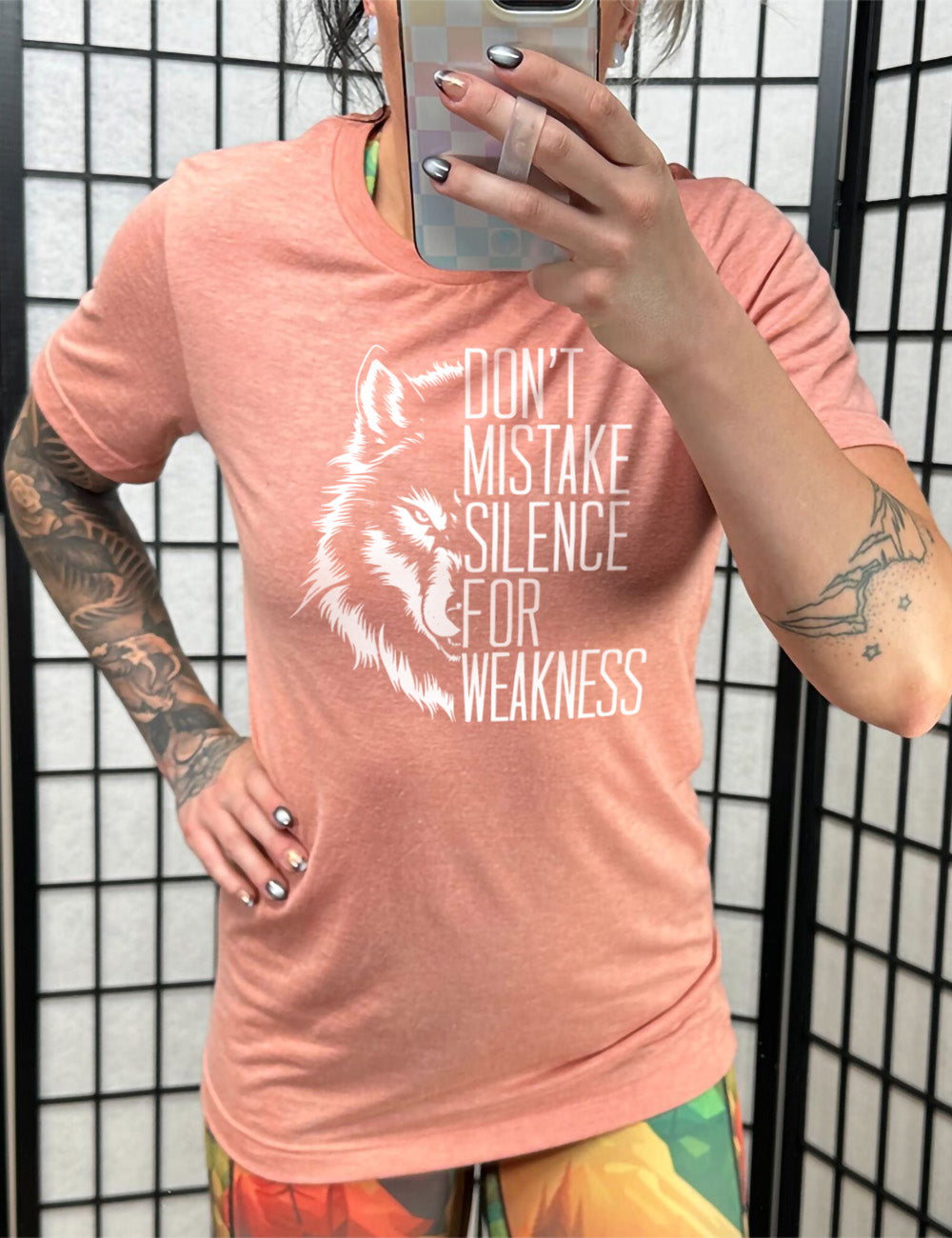 sunset unisex tee with the graphic of half a wolf's head, and the words "don't mistake silence for weakness" making up the other half