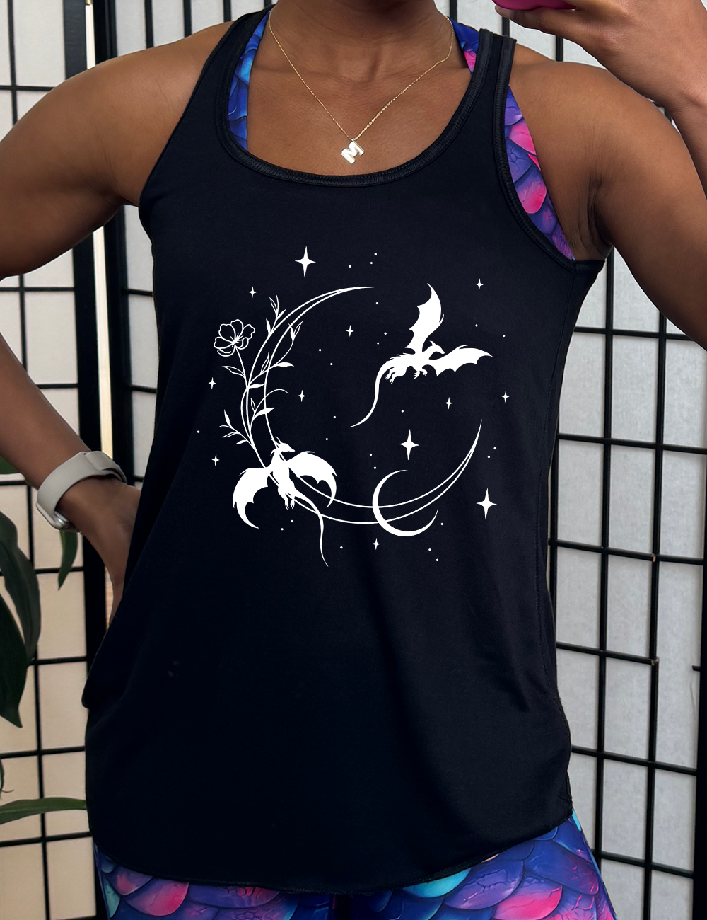black racerback flowy tank with the graphic of a large crescent moon, with a flower lining it, two dragons flying, another smaller moon,  and many small stars