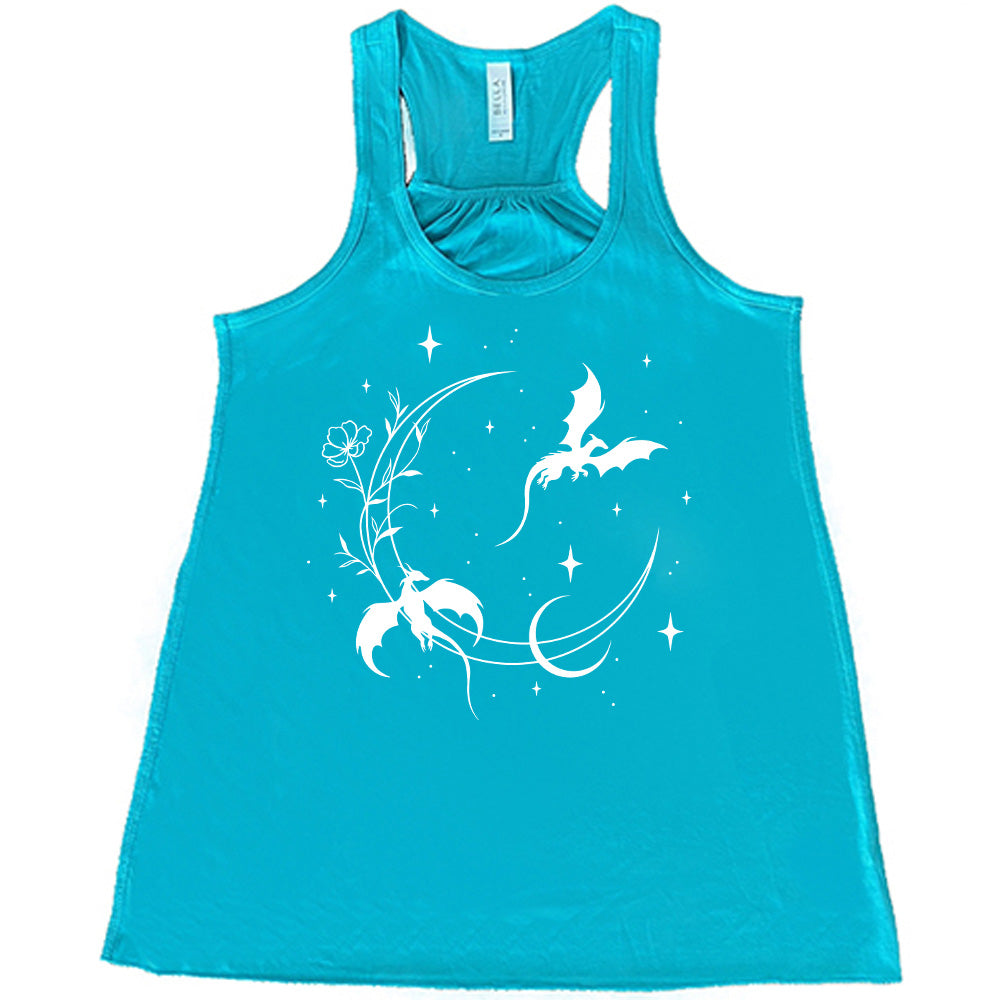 teal racerback flowy tank with the graphic of a large crescent moon, with a flower lining it, two dragons flying, another smaller moon,  and many small stars