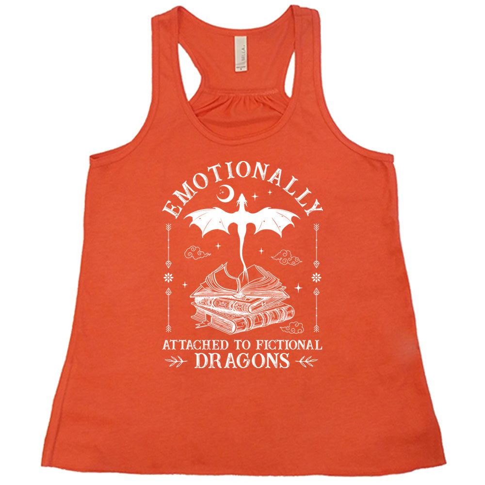 coral racerback flowy tank with the words "emotionally attached to fictional dragons" on it, with graphics of a stack of books, with a dragon flying out of the open book on top, few a few little clouds, a moon, some stars, and arrows and flowers