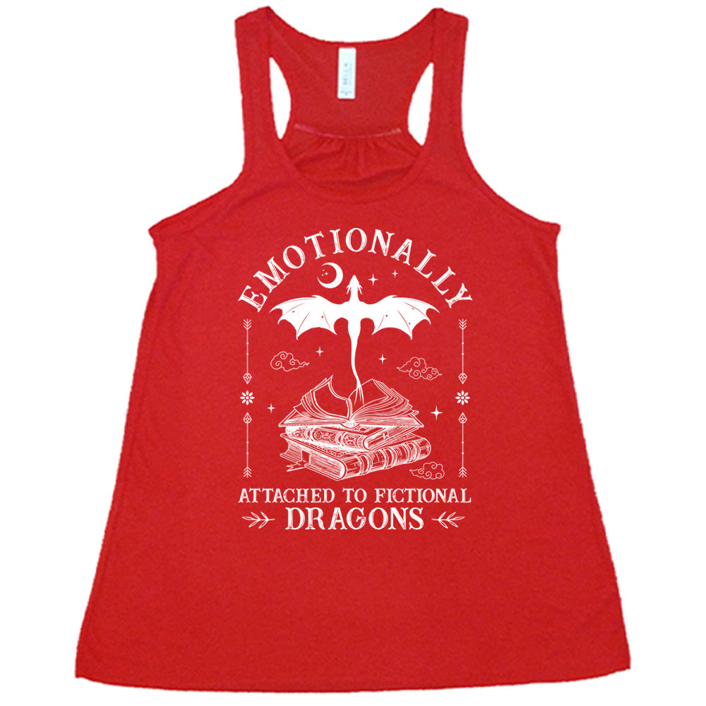 red racerback flowy tank with the words "emotionally attached to fictional dragons" on it, with graphics of a stack of books, with a dragon flying out of the open book on top, few a few little clouds, a moon, some stars, and arrows and flowers