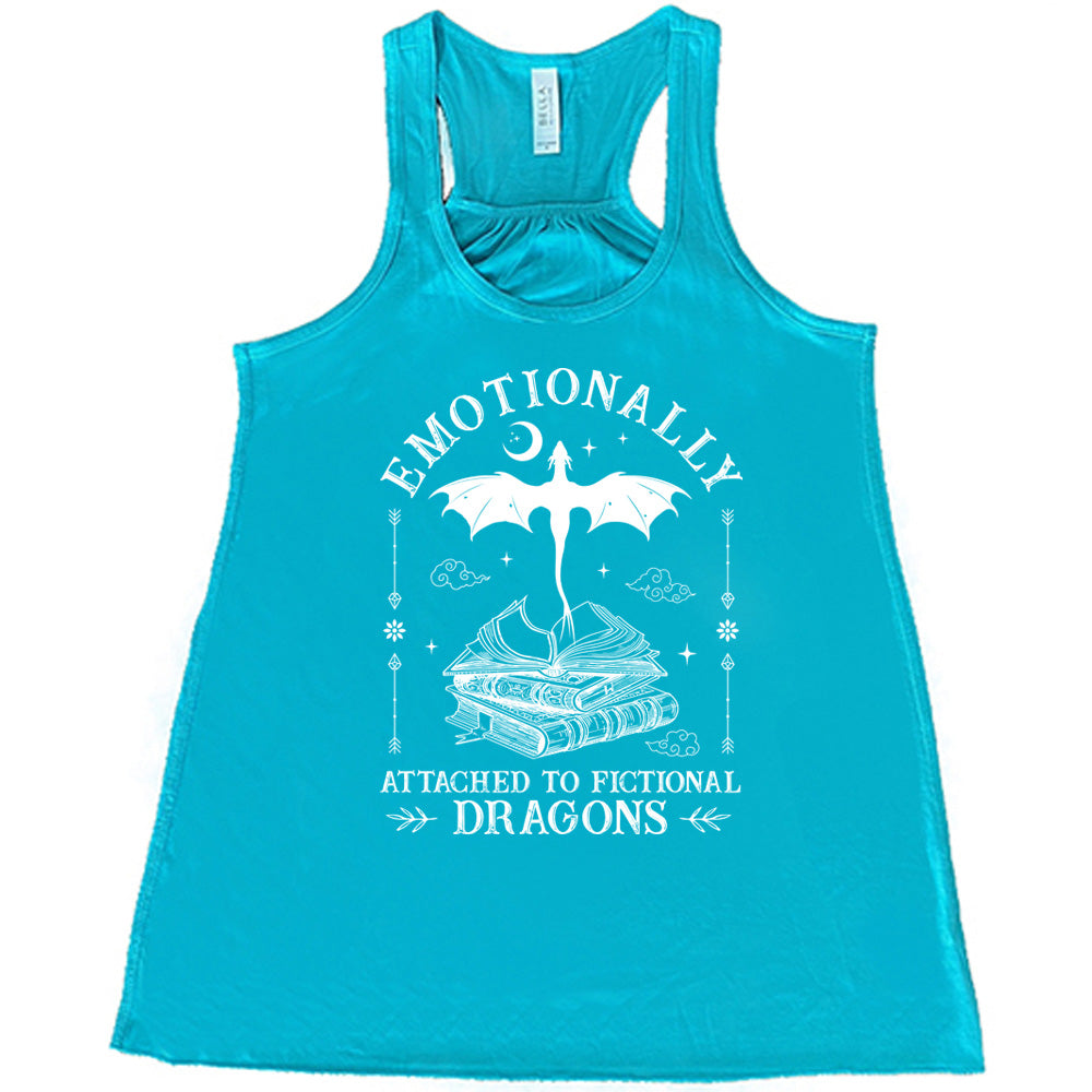 teal racerback flowy tank with the words "emotionally attached to fictional dragons" on it, with graphics of a stack of books, with a dragon flying out of the open book on top, few a few little clouds, a moon, some stars, and arrows and flowers