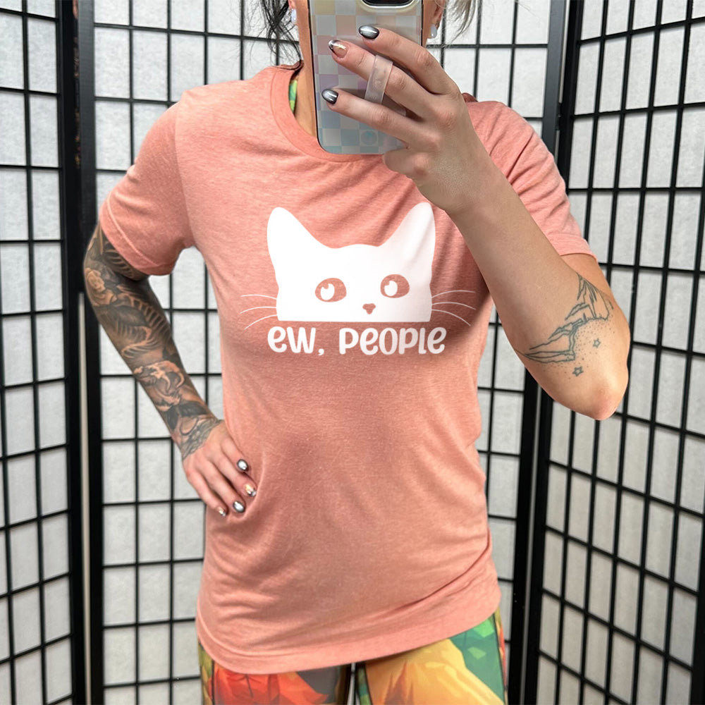 Model wearing sunset colored shirt with cat rolling eyes graphic on it that says "ew, people"