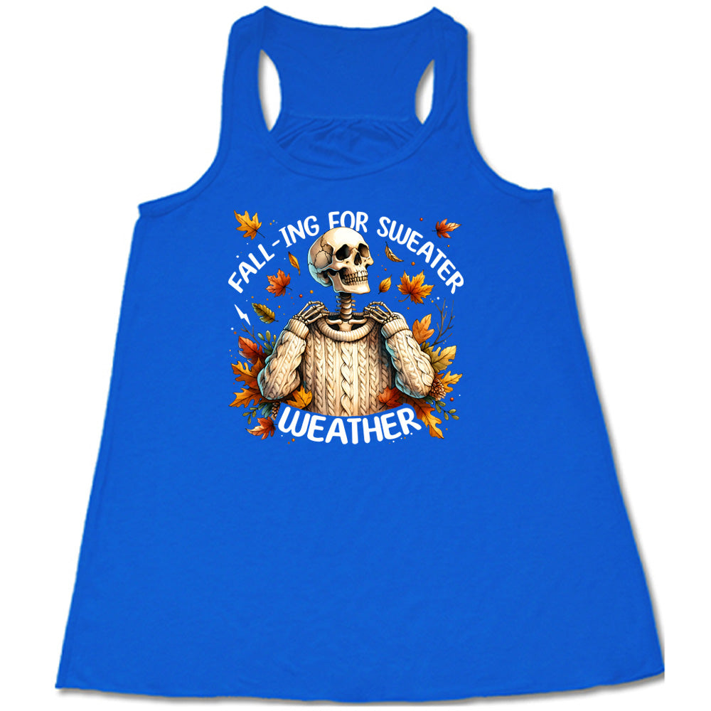 Blue colored flowy tank with fall leaves and skeleton wearing a sweater graphic on it that says "Fall-ing For Sweater Weather"