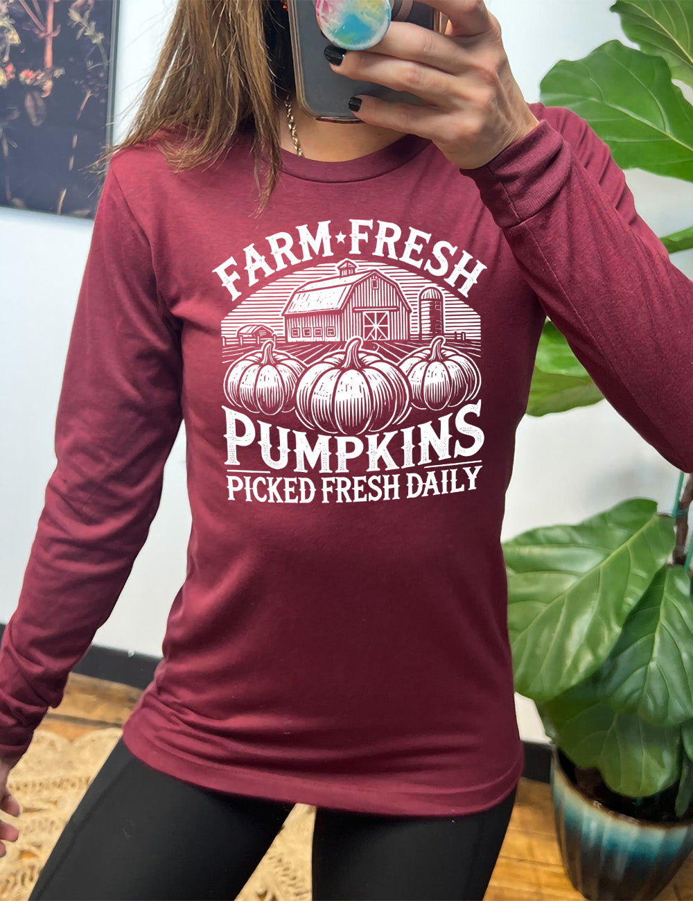 heather cardinal long sleeve shirt with the words "farm fresh pumpkins picked fresh daily" around the graphic of a barn in the background and three pumpkins in the foreground