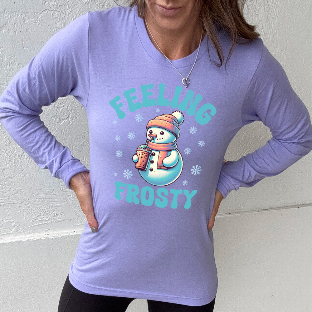 heather dark lavender long sleeve shirt with the words "feeling frosty" on it, with the graphic of snowperson, wearing a hat and scarf, drinking an iced drink, surrounded by snowflakes