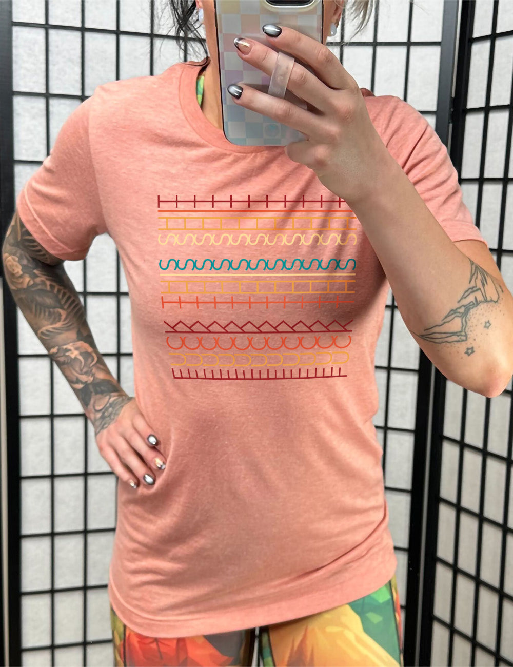 sunset unisex tee with the graphic of what appears to be colorful lined shapes, but, when you look at an angle, actually is the three words, 11 times, sayings "fuck this shit"