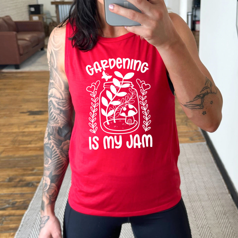 red muscle tank with the words "gardening is my jam" on it, and the graphic of a jar with plants and a mushroom in it, a little butterfly flying above it, and a plant (with hearts for flowers on them) on both sides of it
