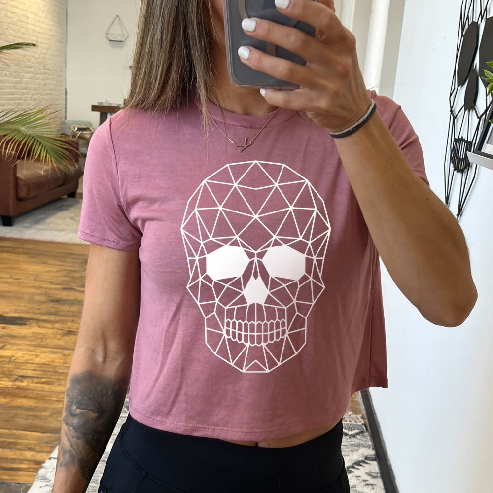 mauve cropped tee with a geometric skull design on the front in white.