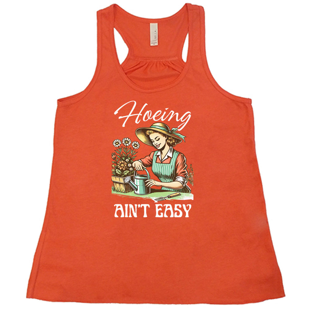 Coral colored flowy tank with a woman gardening graphic on it that says "Hoeing Ain't Easy" 