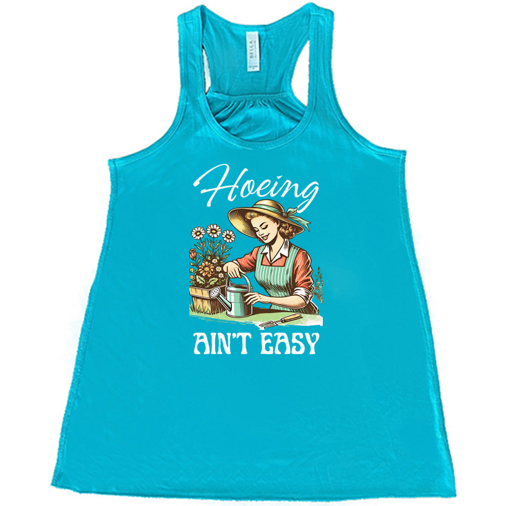 Teal colored flowy tank with a woman gardening graphic on it that says "Hoeing Ain't Easy" 