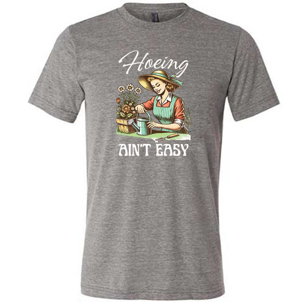 Grey colored shirt with a woman gardening graphic on it that says "Hoeing Ain't Easy"