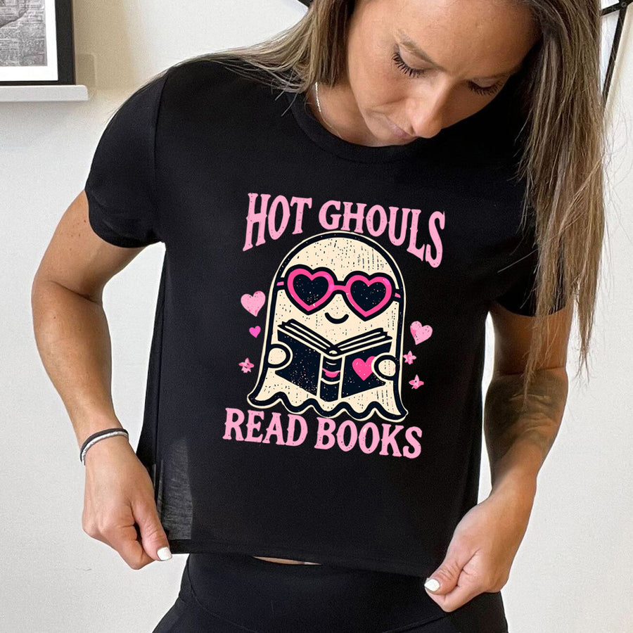 Model wearing black colored cropped tee with the graphic of a ghost wearing heart-shaped glasses holding a book on it, surrounded by hearts, with words on the shirt that say "Hot Ghouls Read Books"