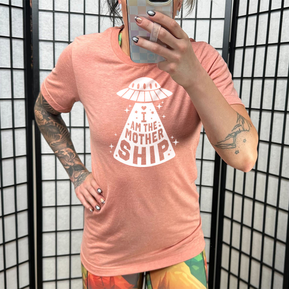 sunset unisex tee with the words "I am the mothership" on it within the beam of a UFO, with a heart above the words, and a number of stars scattered around