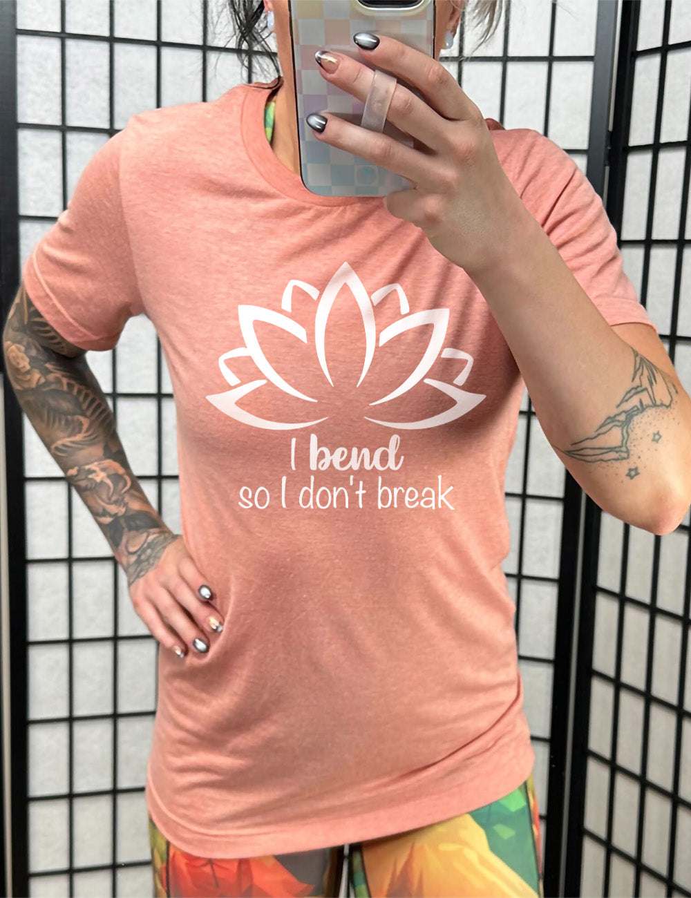 sunset unisex tee with the graphic silhouette of a lotus and the words underneath saying "I bend so I don't break"