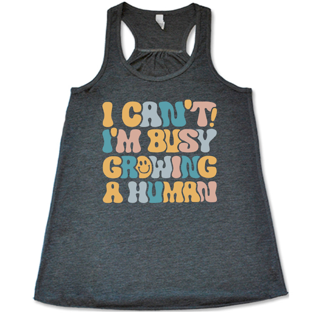 grey racerback flowy tank with the words "I can't! I'm busy growing a human" on it in colorful font, with a smiley face in the "o" of the word "growing"