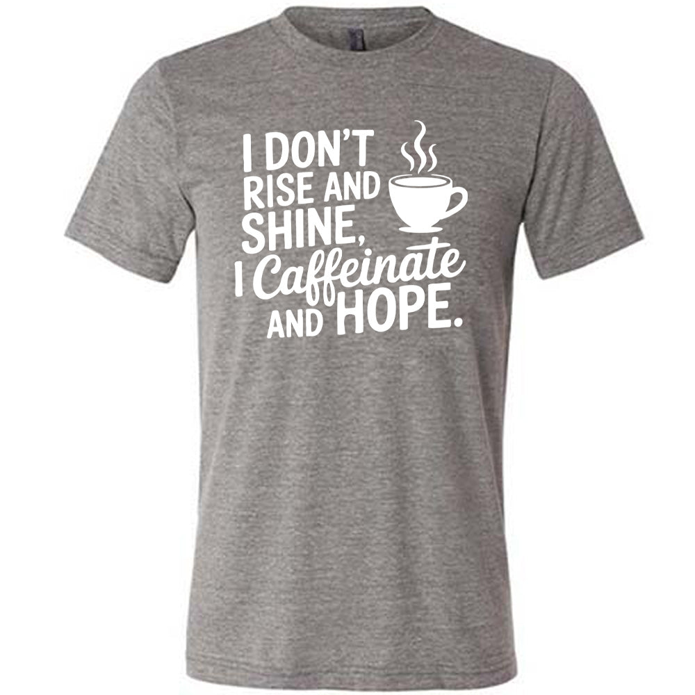 grey unisex tee with the words "I don't rise and shine, I caffeinate and HOPE." on it, with the graphic of a steaming cup of a coffee