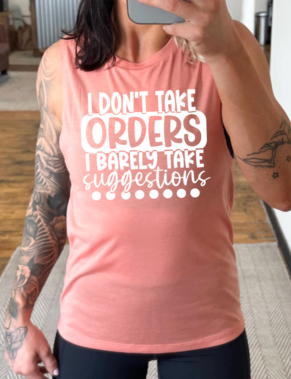 peach muscle tank with the words "I don't take orders I barely take suggestions" on it, with a row of dots underneath