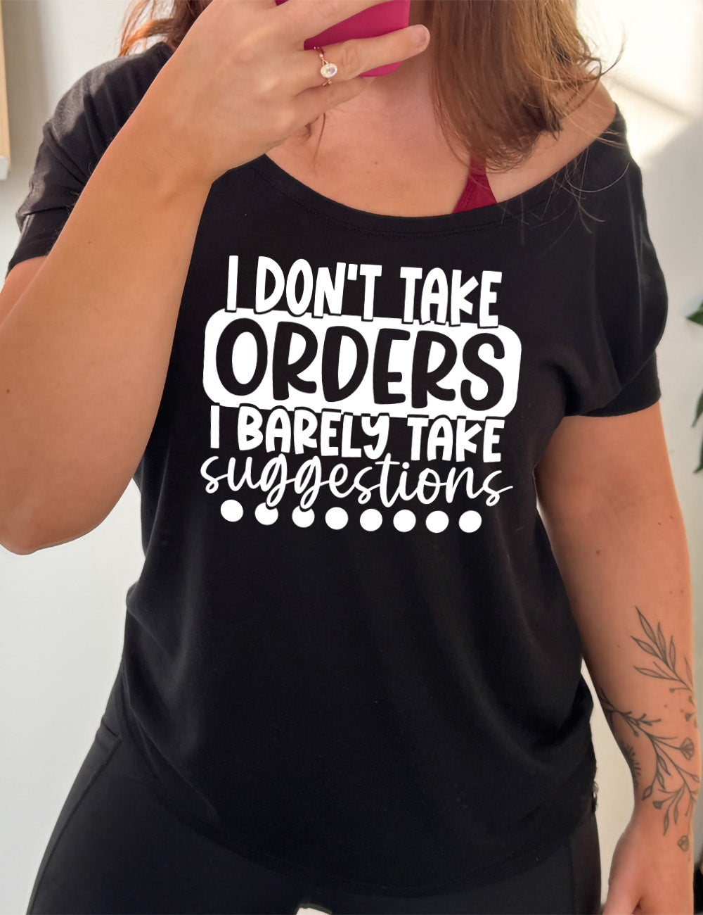 black slouchy tee with the words "I don't take orders I barely take suggestions" on it, with a row of dots underneath