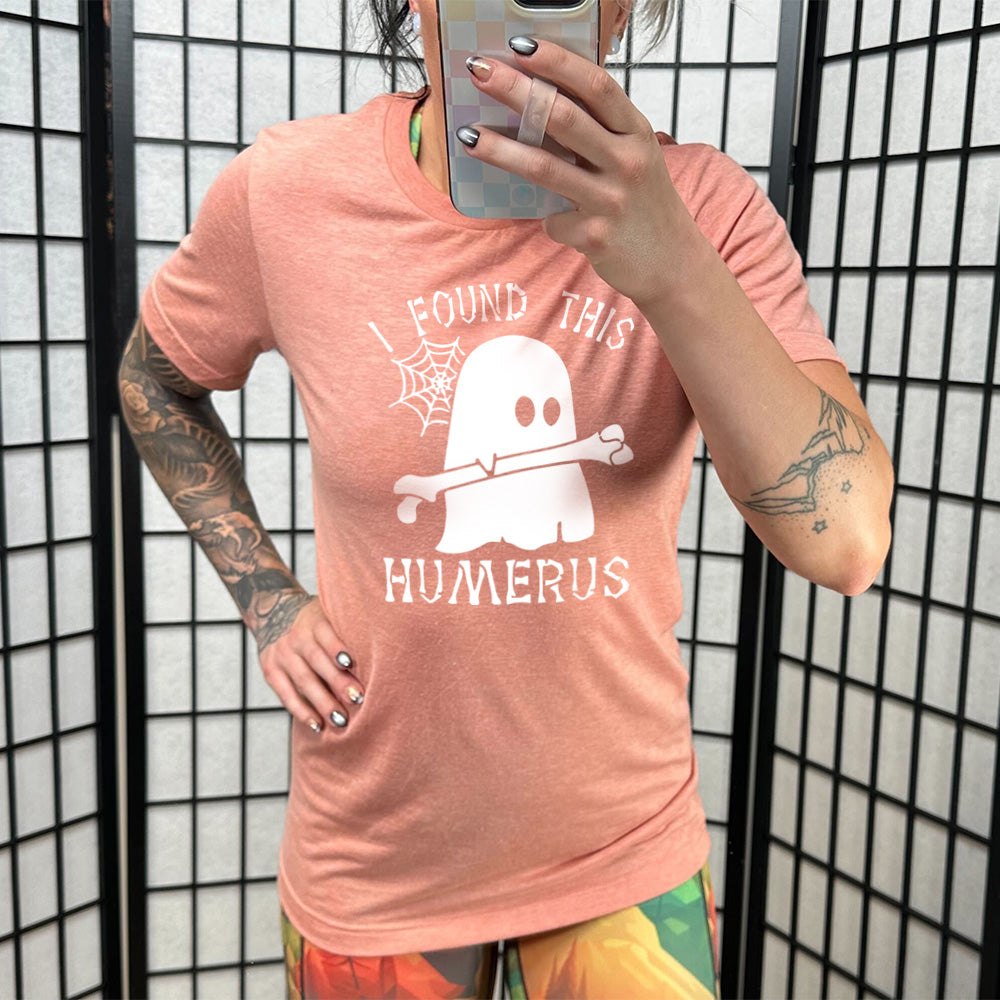 Model wearing sunset colored shirt with ghost holding a bone graphic on it that says "I Found This Humerus"