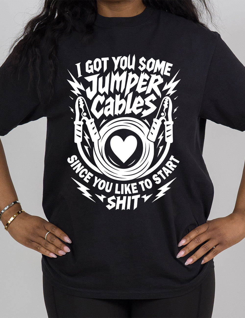 black modern tee with the words "I got you some jumper cables since you like to start shit" on it, with the graphic of jumper cables, with the cables rolled around a heart, and the words embellished by electric bolt graphics