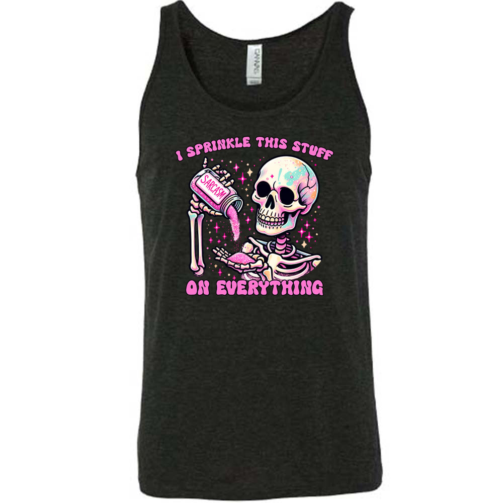 black unisex tank with the words "I sprinkle this stuff on everything" on it, and the graphic of a skeleton who is pouring a jar labeled "sarcasm" filled with pink glittery material into its hand, surrounded by little pink and white stars