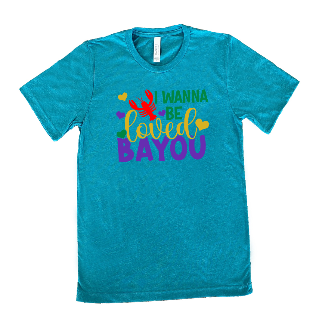 teal unisex tee with the words "I wanna be loved bayou" on it in varied fonts, with the small graphics a few hearts and one lobster