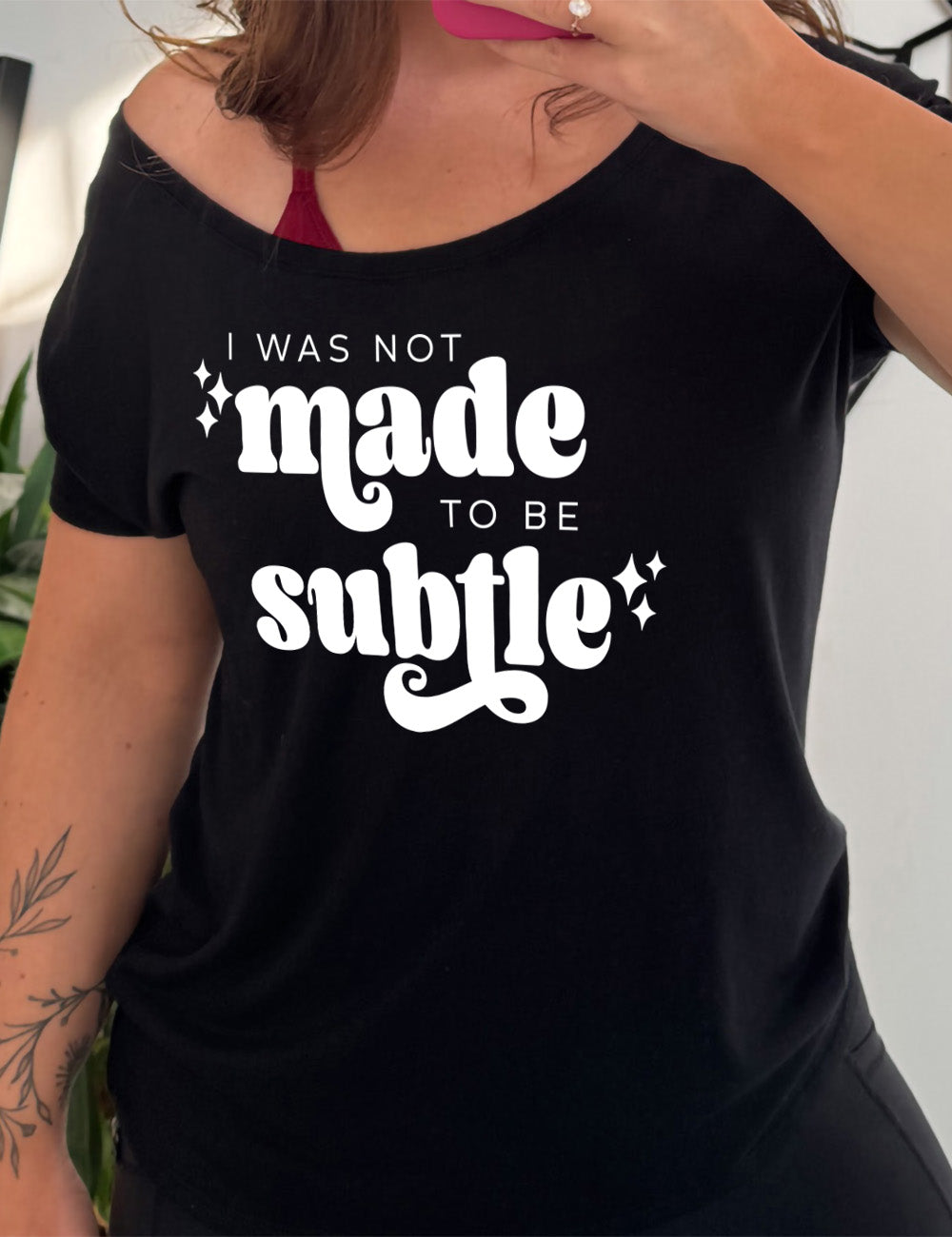 black slouchy tee with the words "I was not made to be subtle" on it, with a few stars embellishing