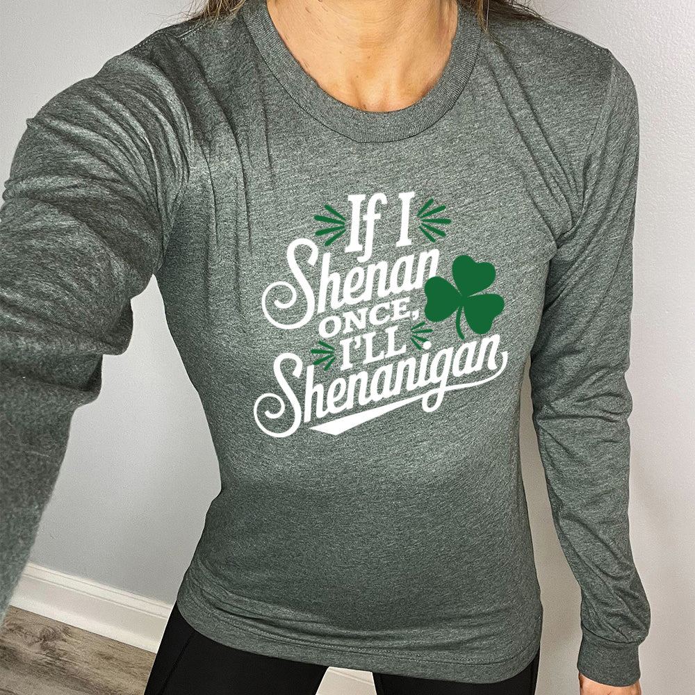 heather forest long sleeve with the words "if I shenan once, I'll shenanigan" on it, with the graphic of a shamrock