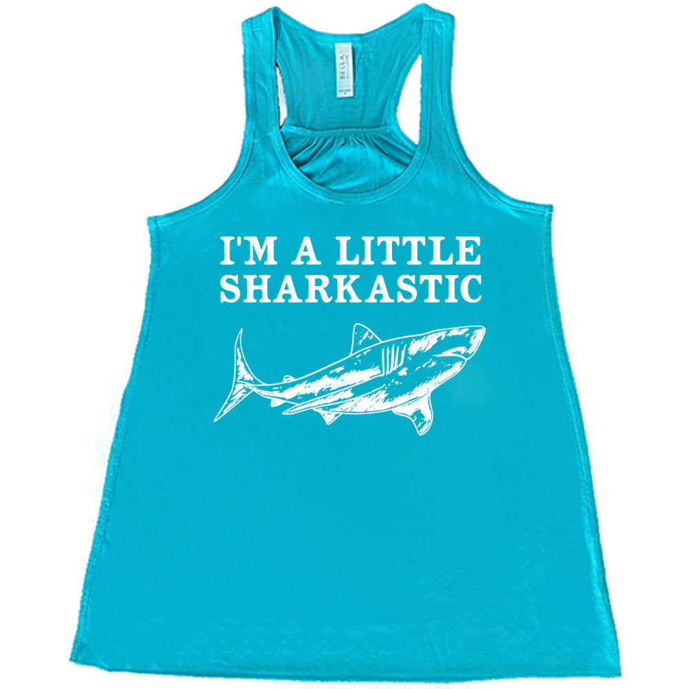 teal racerback flowy tank with the words "I'm a little sharkastic" on it, over the graphic of a shark