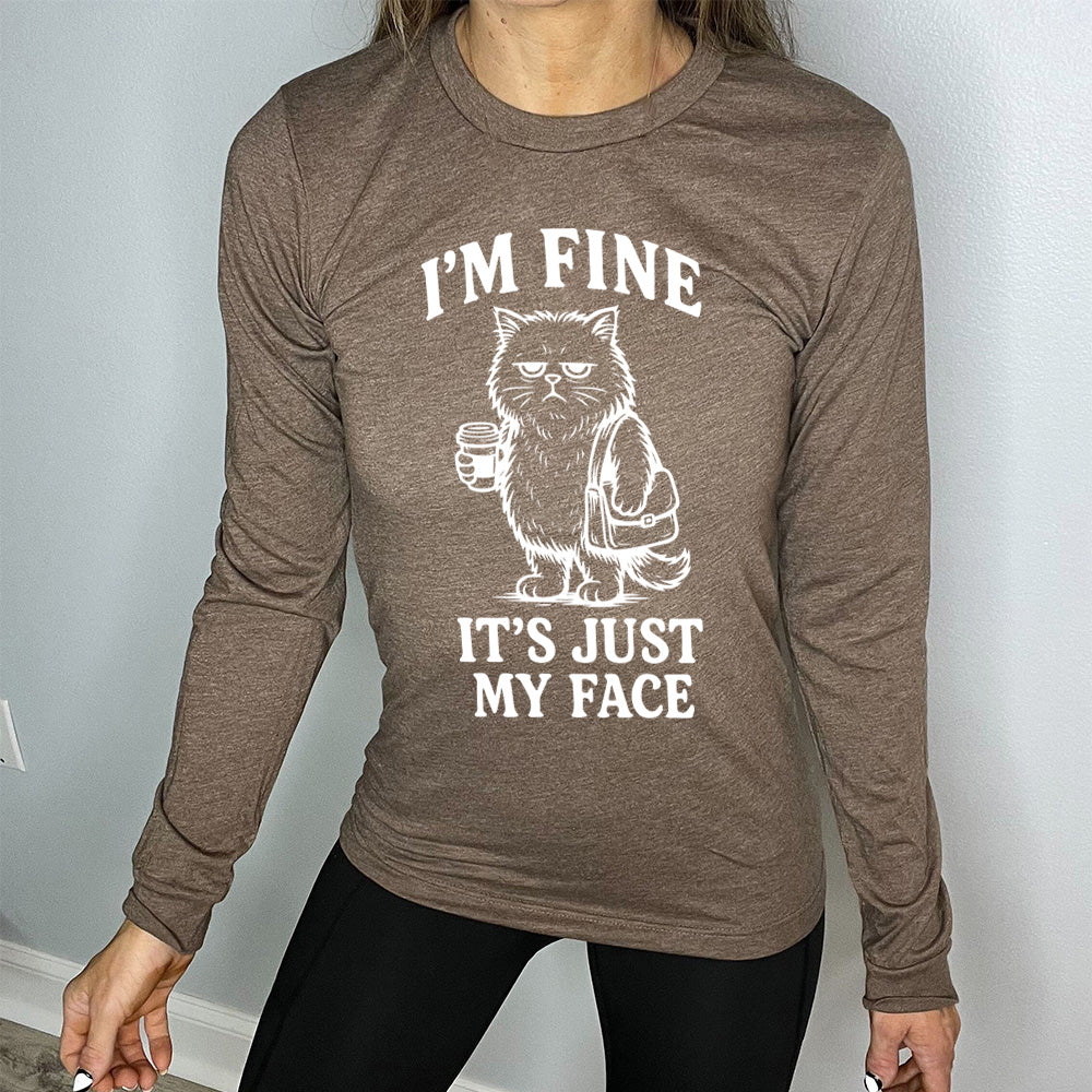 heather brown long sleeve shirt with the words "I'm fine it's just my face" on it, around the graphic of a cat with a resting-grumpy face, holding a coffee and wearing a purse