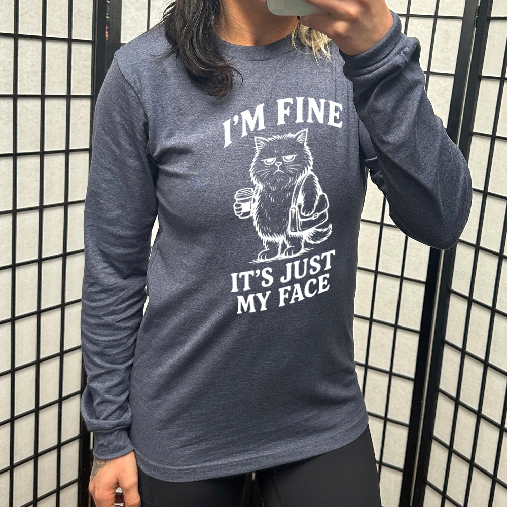 heather navy long sleeve shirt with the words "I'm fine it's just my face" on it, around the graphic of a cat with a resting-grumpy face, holding a coffee and wearing a purse