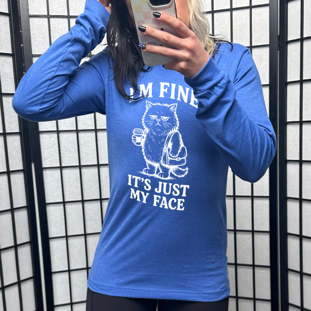 heather true royal long sleeve shirt with the words "I'm fine it's just my face" on it, around the graphic of a cat with a resting-grumpy face, holding a coffee and wearing a purse