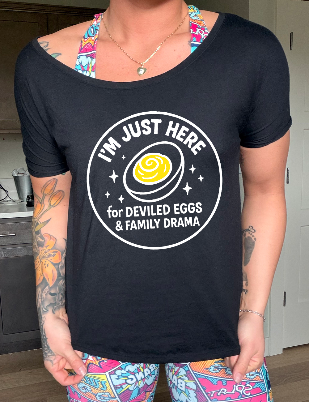 black slouchy tee with the words "I'm just here for the deviled eggs & family drama" on it within a circle, with the graphic of a deviled egg and a few little stars