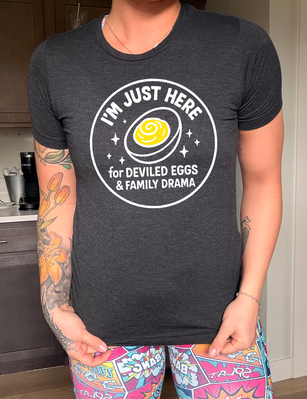 black unisex tee with the words "I'm just here for the deviled eggs & family drama" on it within a circle, with the graphic of a deviled egg and a few little stars