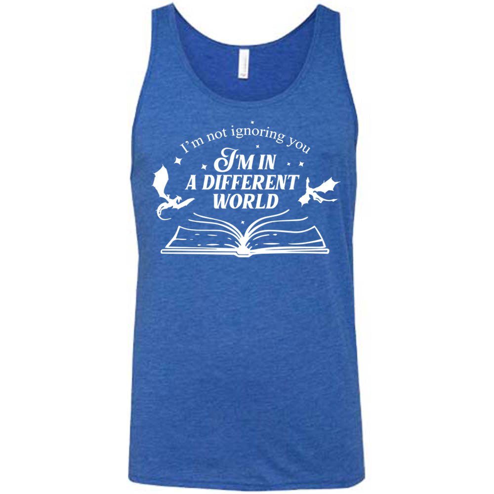 blue unisex tank with the words "I'm not ignoring you I'm in a different world" on it, with the graphic of a large book, lying open, and two little dragons flying next to the words, a few stars scattered around