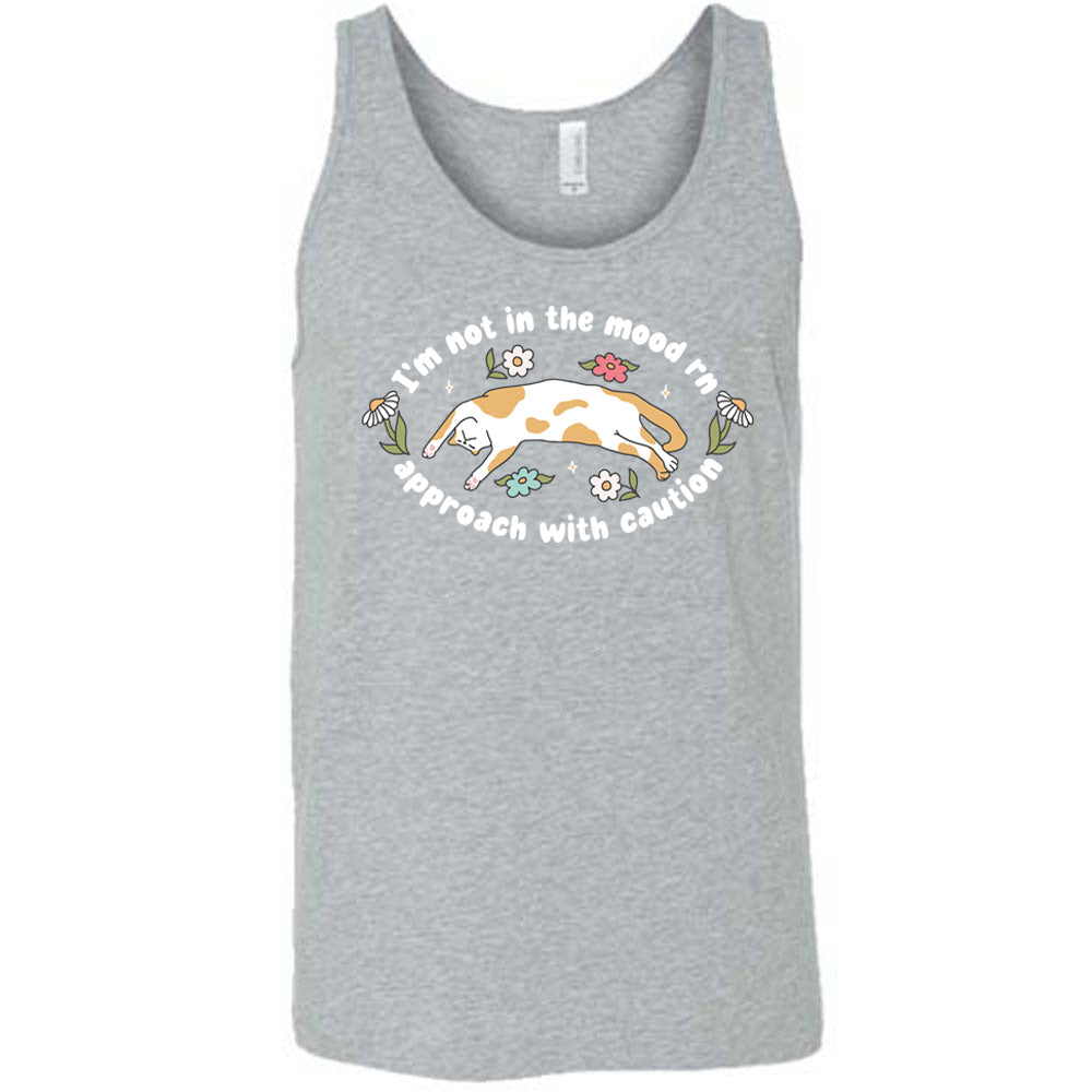 grey unisex tank with the words "I'm not in the mood rn approach with caution" on it in an oval, with the graphic of a cat splayed on its back within the words, and a few flowers around
