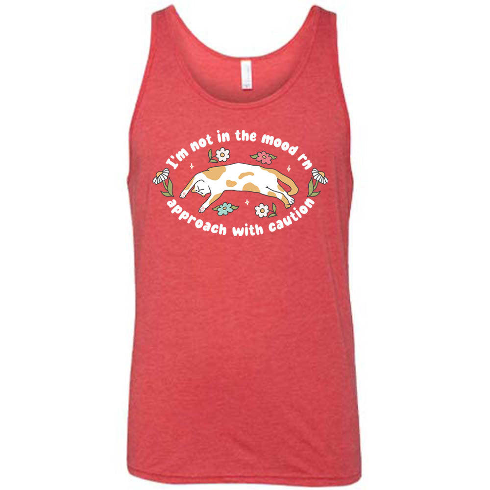 red unisex tank with the words "I'm not in the mood rn approach with caution" on it in an oval, with the graphic of a cat splayed on its back within the words, and a few flowers around