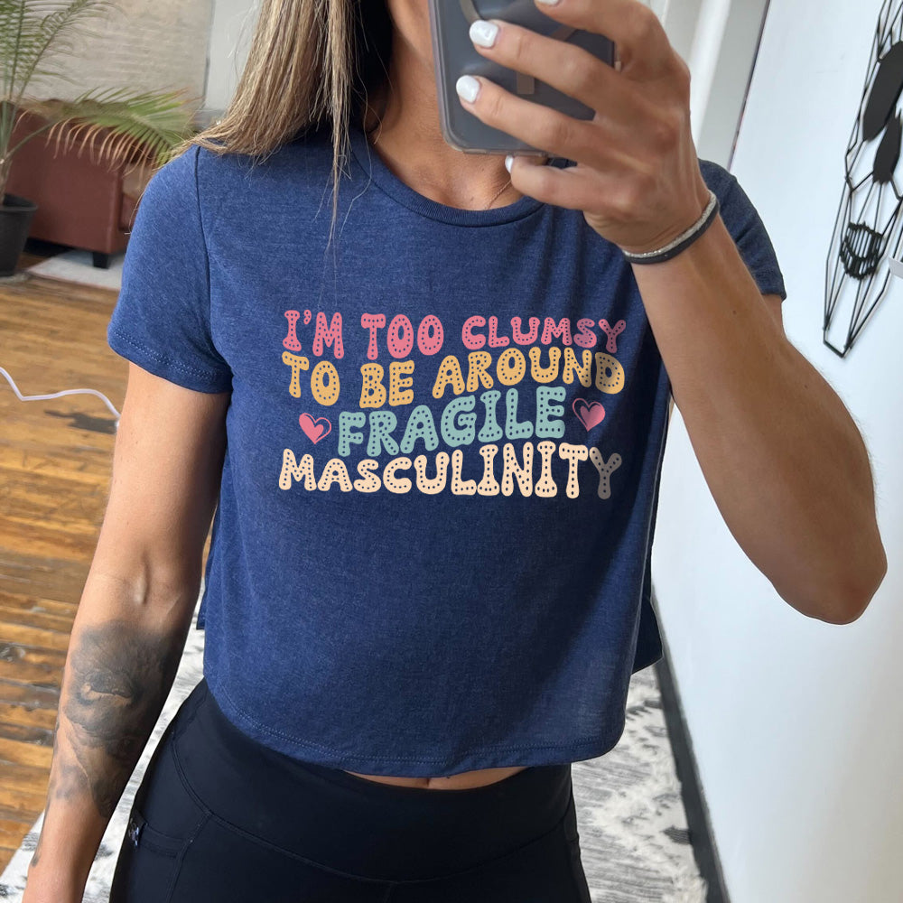 heather navy cropped tee with a graphic on it that says "I'm Too Clumsy To Be Around Fragile Masculinity" 