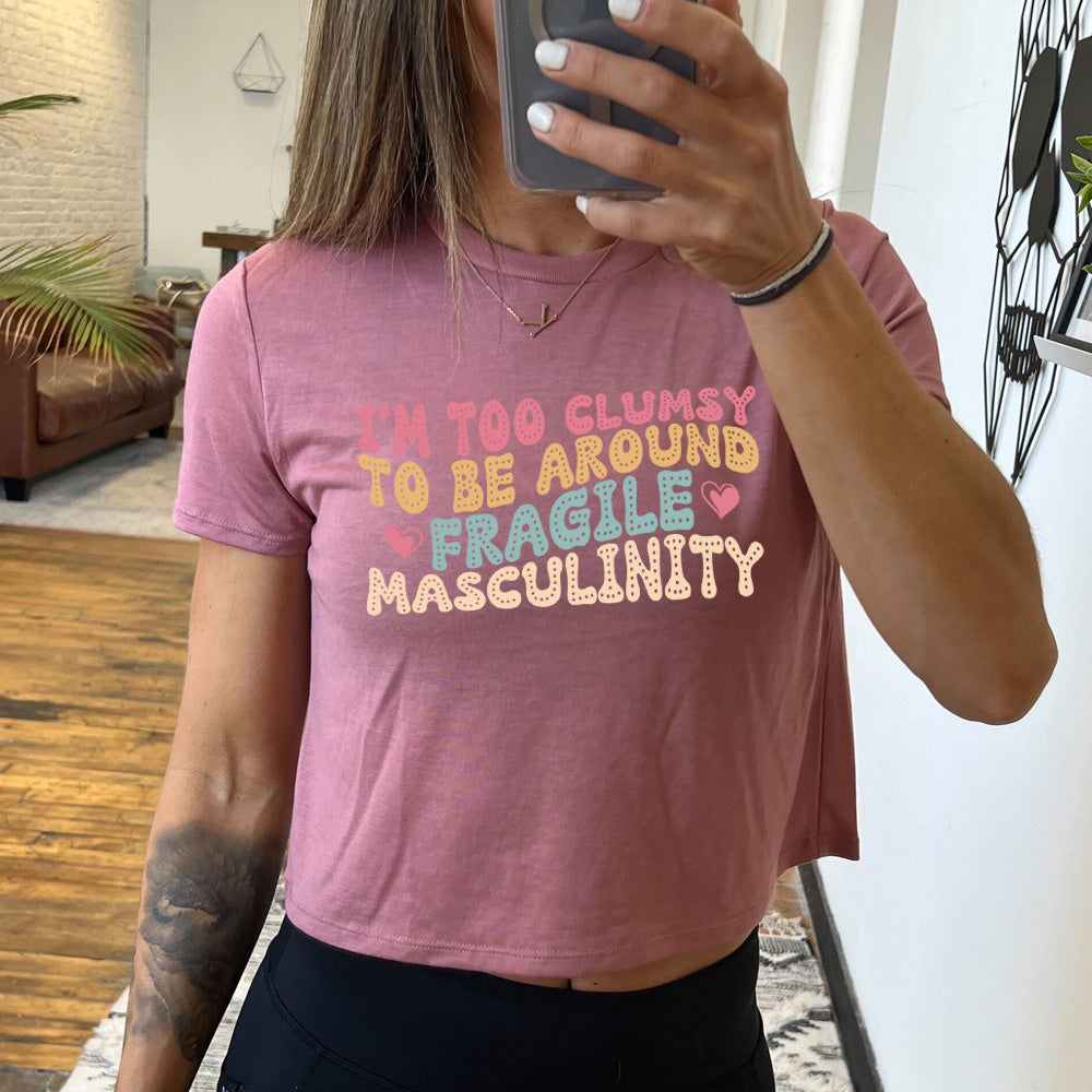 mauve cropped tee with a graphic on it that says "I'm Too Clumsy To Be Around Fragile Masculinity" 