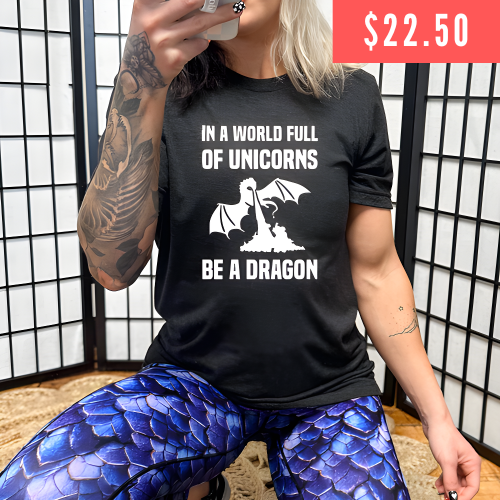 $22.50 black unisex shirt with the saying "In A World Full Of Unicorns Be A Dragon" on it in white