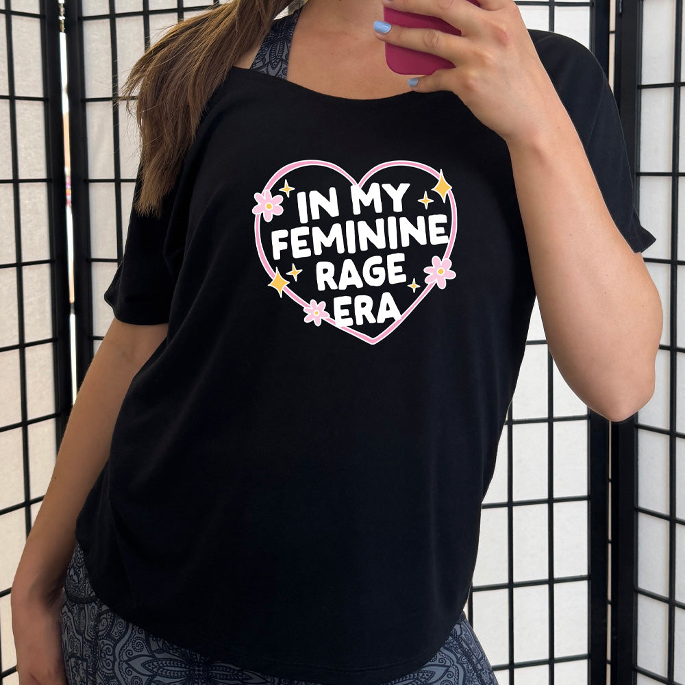 black slouchy tee with the words "in my feminine rage era" within a heart, with scattered flowers and stars