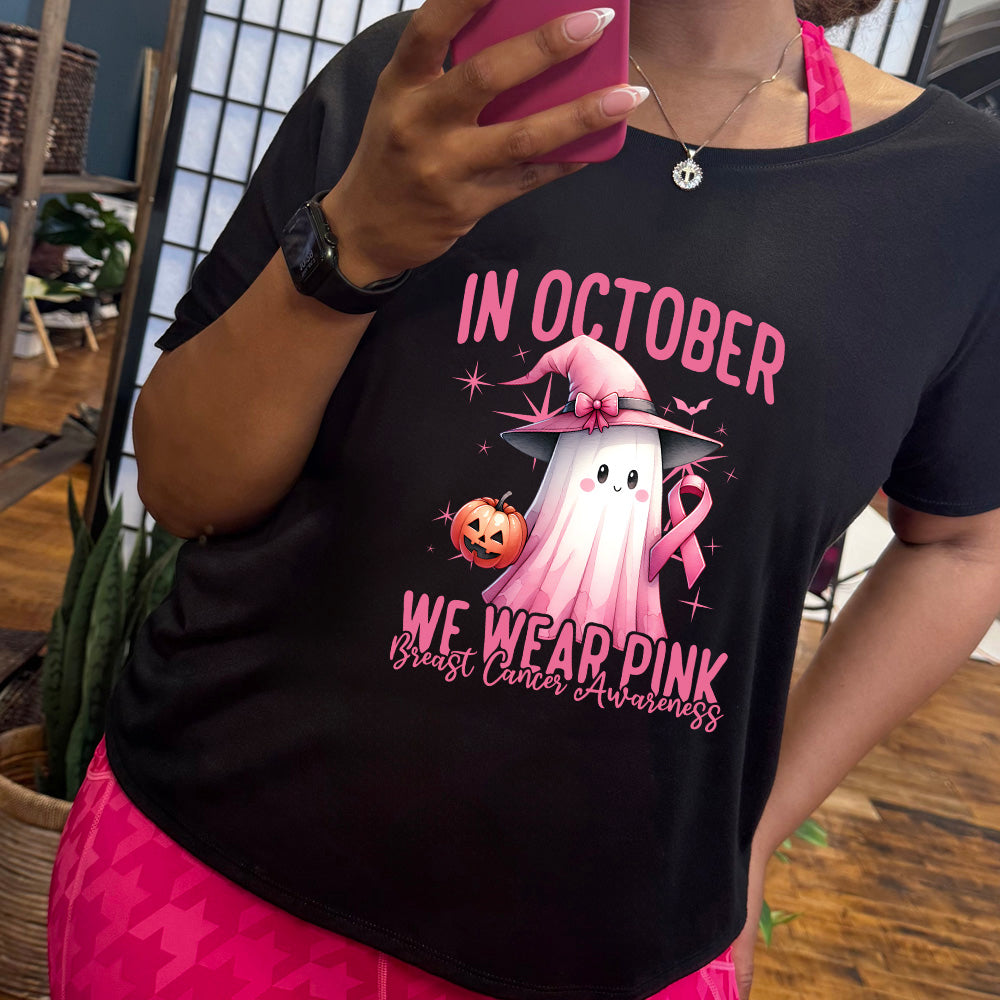 Person wearing a black t-shirt with a pink ghost graphic and text about breast cancer awareness.